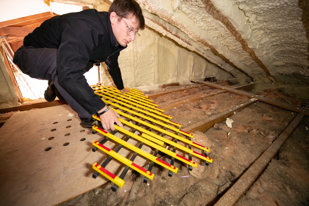 A professional contractor in protective gear applying spray foam insulation to the interior of a home's attic, showcasing modern home energy solutions.